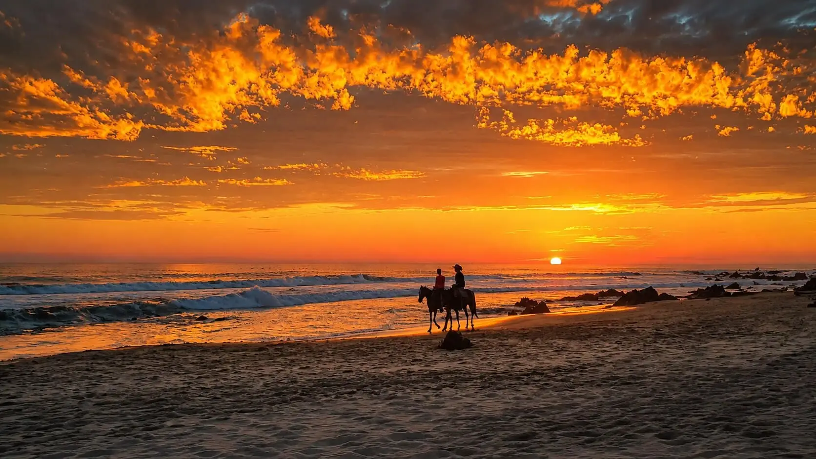 Riders on Troncones beach at sunset
